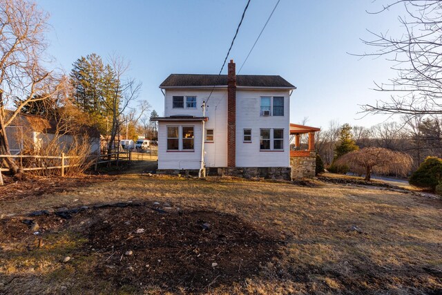 back of house with a chimney and fence