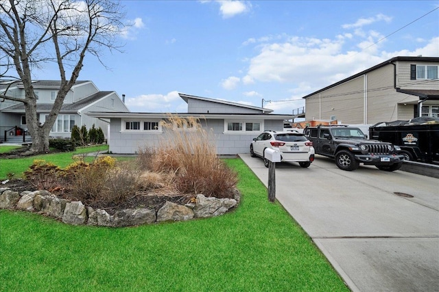 view of front of property featuring concrete driveway and a front lawn