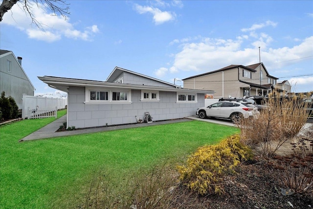 exterior space with concrete block siding, fence, and a front yard