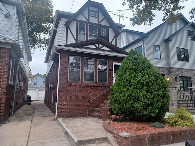 tudor house featuring a garage, brick siding, and an outdoor structure