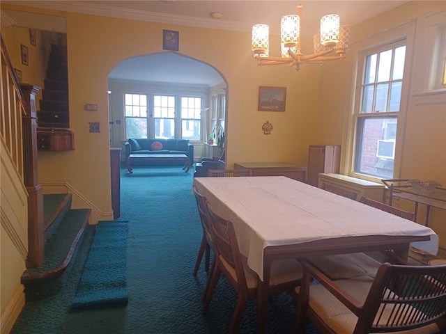 carpeted dining room featuring arched walkways, ornamental molding, stairs, and a notable chandelier