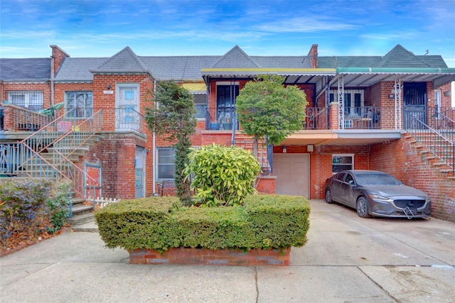 townhome / multi-family property with stairs, concrete driveway, brick siding, and an attached garage