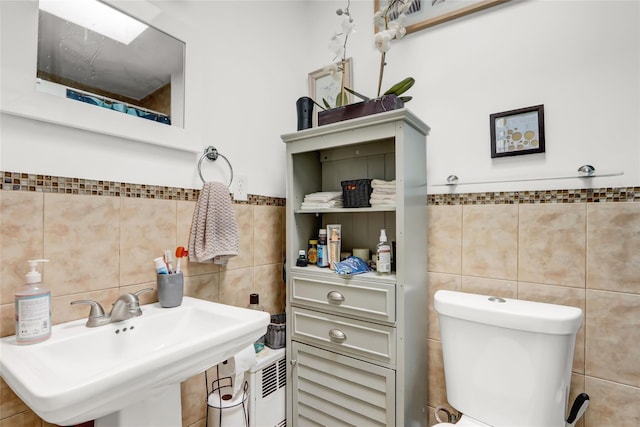 bathroom with toilet, tile walls, and a sink