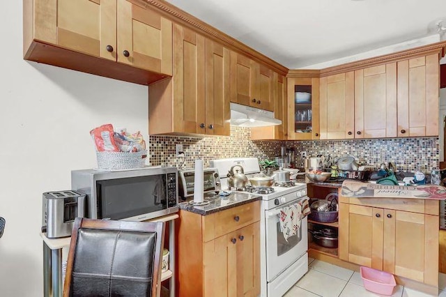 kitchen with stainless steel microwave, tasteful backsplash, gas range gas stove, and under cabinet range hood