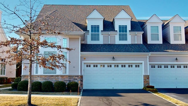 multi unit property featuring aphalt driveway, stone siding, and roof with shingles