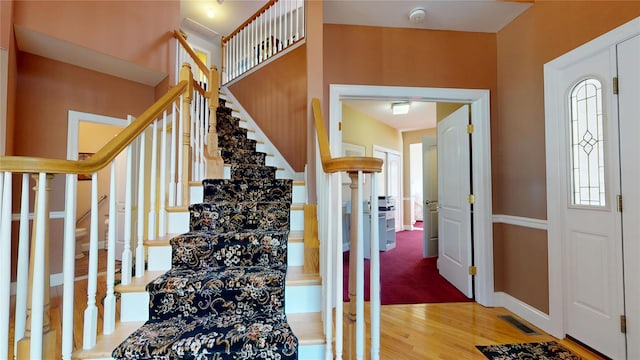 stairway featuring visible vents, baseboards, and wood finished floors