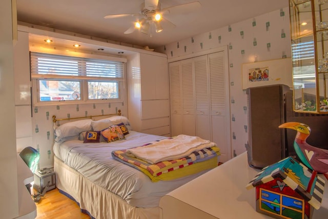 bedroom featuring wallpapered walls, a ceiling fan, a closet, and light wood finished floors