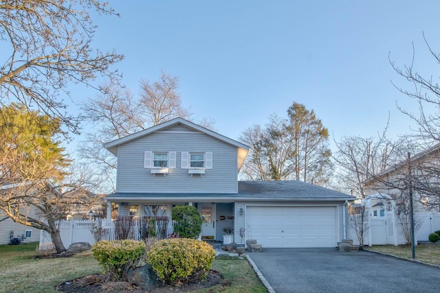 traditional-style home with a porch, driveway, a garage, and fence