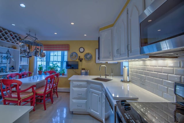 kitchen with stainless steel microwave, light countertops, light tile patterned floors, decorative backsplash, and a sink