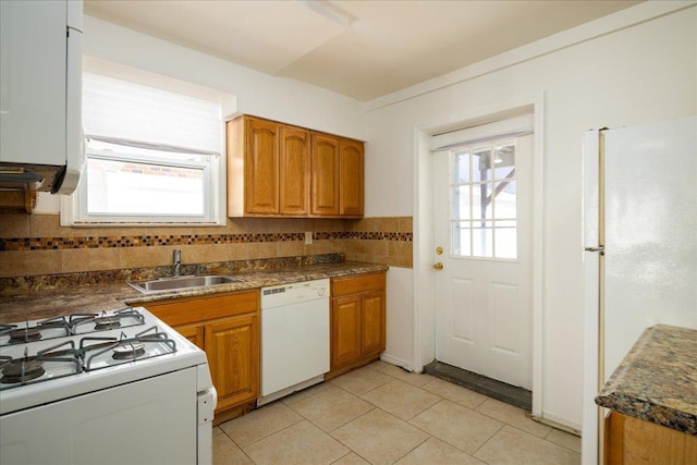 kitchen with a sink, white appliances, decorative backsplash, and a healthy amount of sunlight