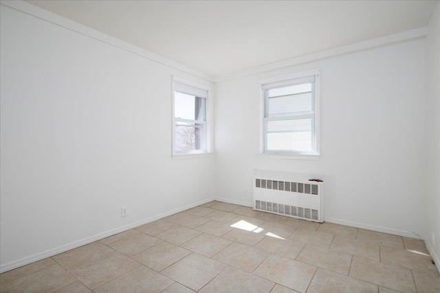 unfurnished room featuring crown molding, light tile patterned floors, radiator heating unit, and baseboards