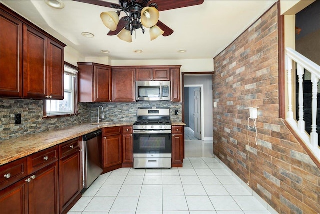 kitchen featuring light tile patterned floors, tasteful backsplash, appliances with stainless steel finishes, a sink, and brick wall