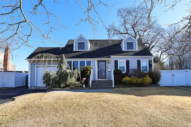 cape cod home with aphalt driveway, fence, a garage, and a front lawn