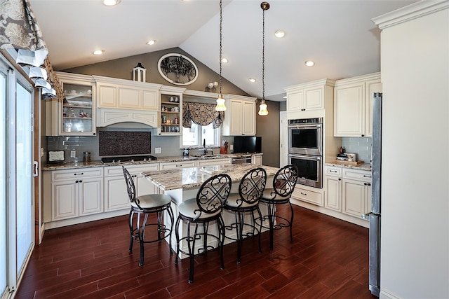 kitchen featuring a breakfast bar, dark wood finished floors, a kitchen island, and stainless steel double oven