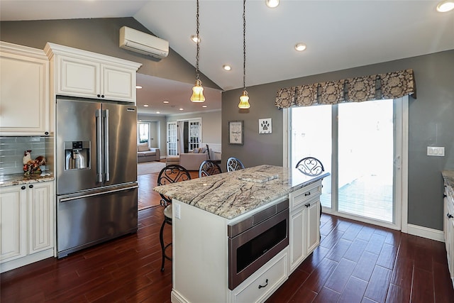 kitchen with a kitchen bar, dark wood finished floors, appliances with stainless steel finishes, and a wall mounted AC