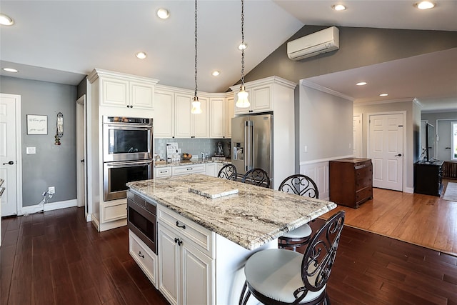 kitchen featuring light stone countertops, appliances with stainless steel finishes, a breakfast bar, and a wall mounted AC