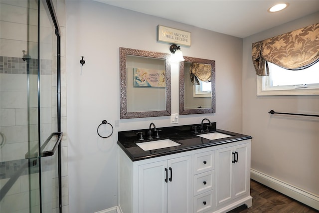 bathroom with a sink, a baseboard radiator, double vanity, and a shower stall