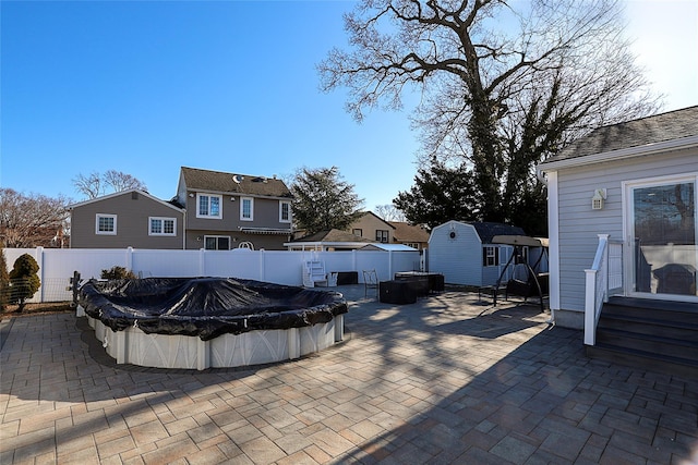 view of patio with a fenced in pool, an outbuilding, a storage shed, and a fenced backyard