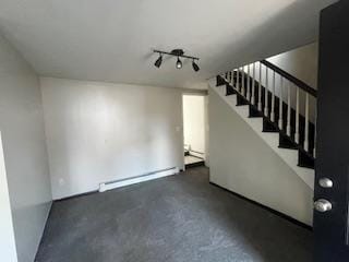 basement featuring a baseboard heating unit, stairway, and track lighting