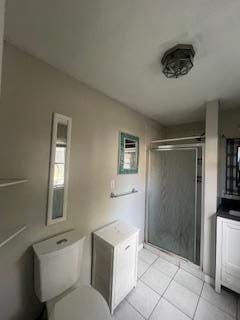 full bath featuring a stall shower, tile patterned flooring, and toilet