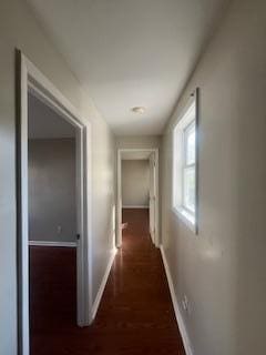 corridor with dark wood-style flooring and baseboards