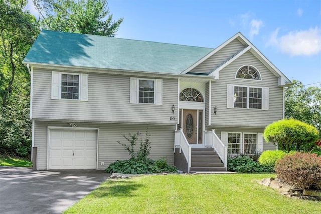 split foyer home featuring a garage, a front lawn, and aphalt driveway