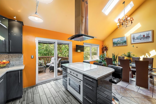 kitchen featuring backsplash, island range hood, a chandelier, and dark cabinetry