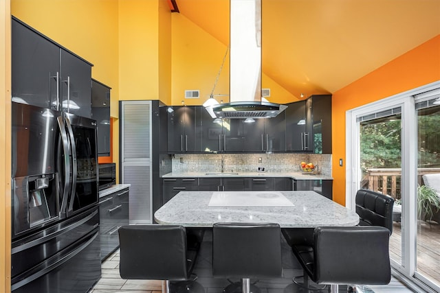 kitchen featuring dark cabinets, a sink, island exhaust hood, and black appliances