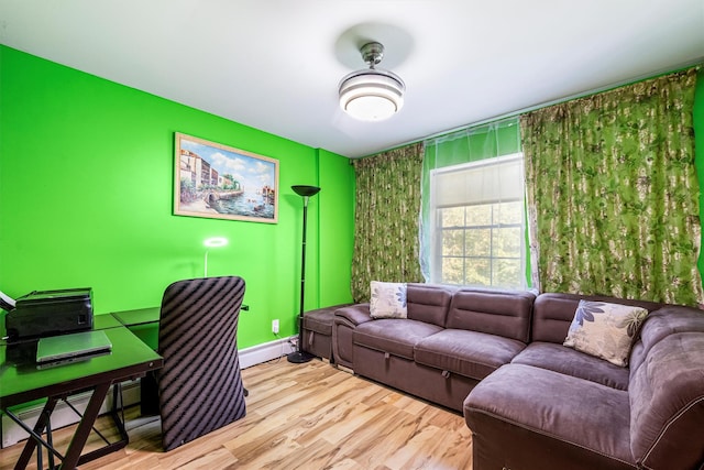 living area featuring a baseboard radiator, an accent wall, baseboards, and wood finished floors