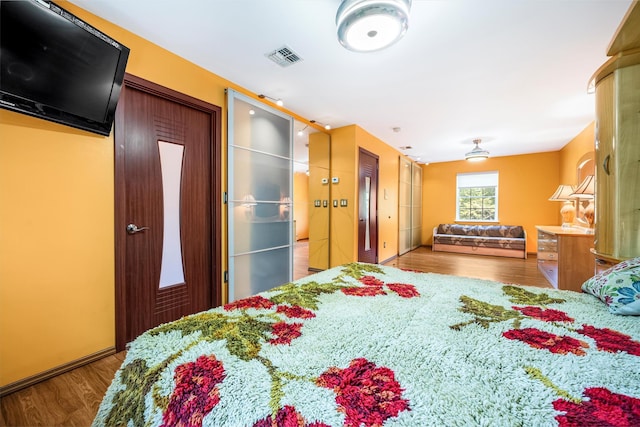 bedroom featuring wood finished floors and visible vents