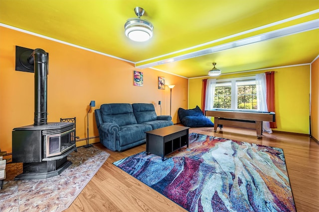 living room with baseboard heating, wood finished floors, and a wood stove