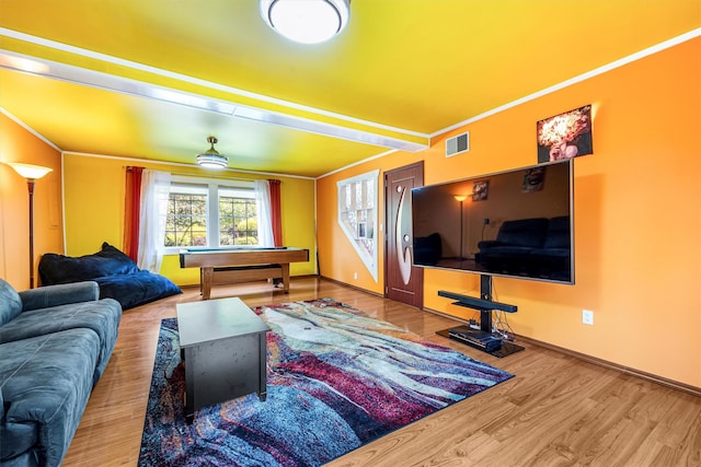 living area featuring visible vents, crown molding, baseboards, and wood finished floors