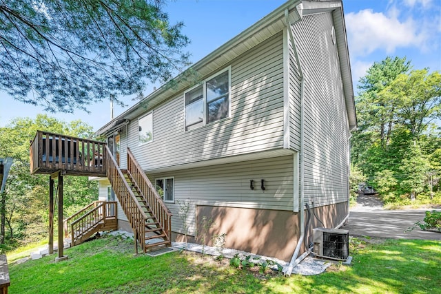 rear view of property featuring a deck, central AC, a yard, and stairway