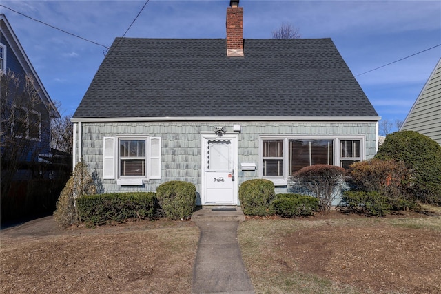 cape cod home with a chimney and roof with shingles