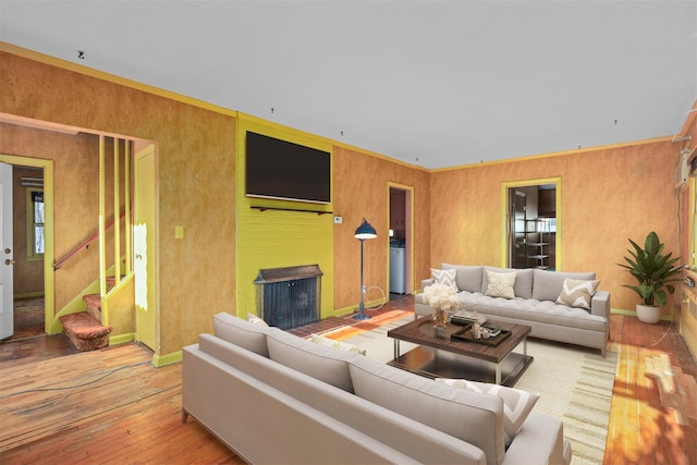 living room featuring stairs, hardwood / wood-style flooring, a fireplace, and baseboards