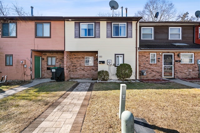 view of property with brick siding and a front yard