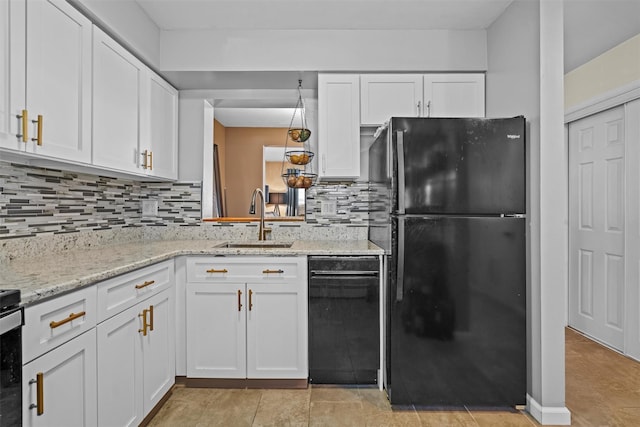 kitchen featuring white cabinets, backsplash, freestanding refrigerator, and a sink