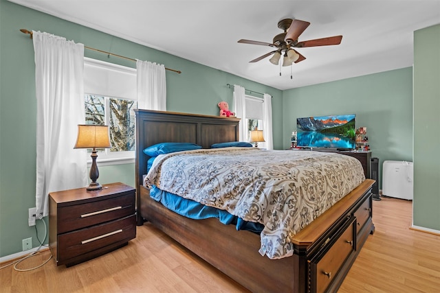 bedroom featuring multiple windows, light wood-style floors, and baseboards