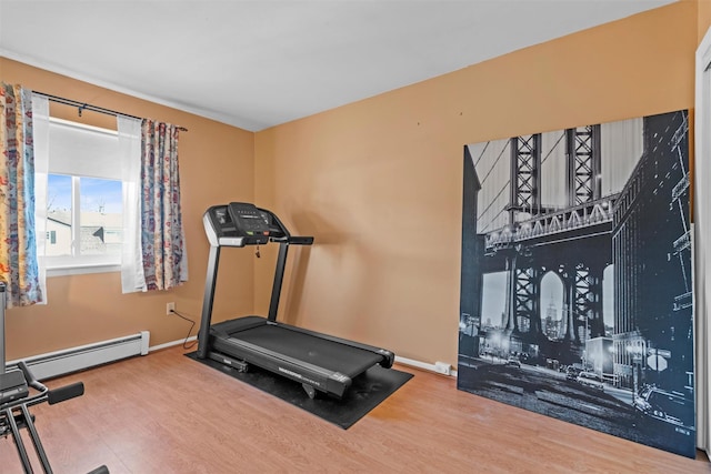 workout area featuring wood finished floors, baseboards, and a baseboard radiator