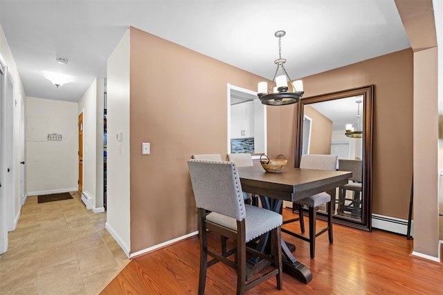 dining space featuring baseboards, baseboard heating, a chandelier, and light wood finished floors