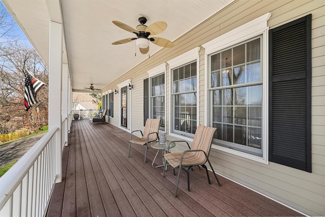 wooden terrace featuring covered porch and a ceiling fan