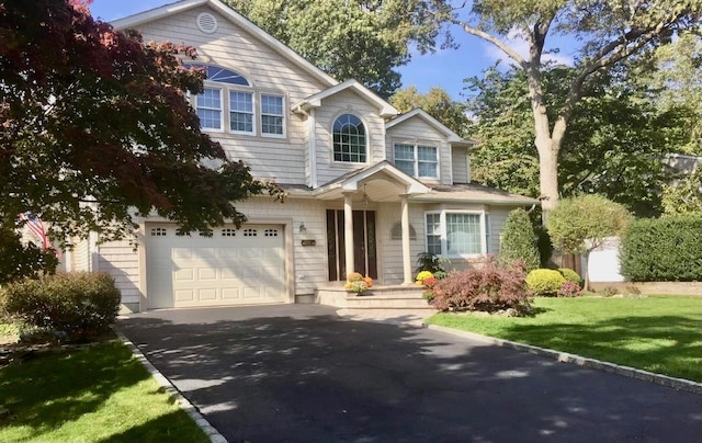 view of front of house with aphalt driveway, a garage, and a front lawn