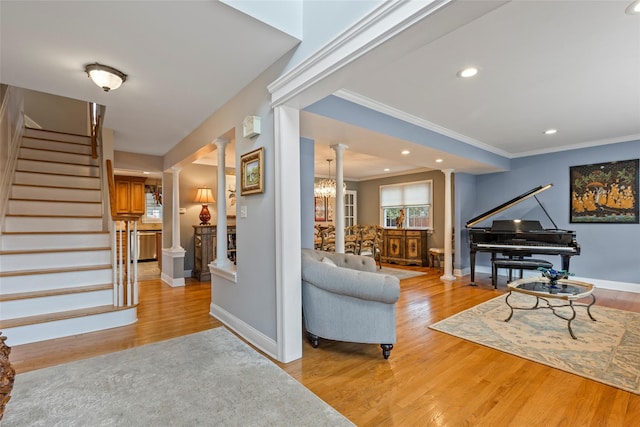 interior space featuring stairway, crown molding, light wood-style floors, and ornate columns