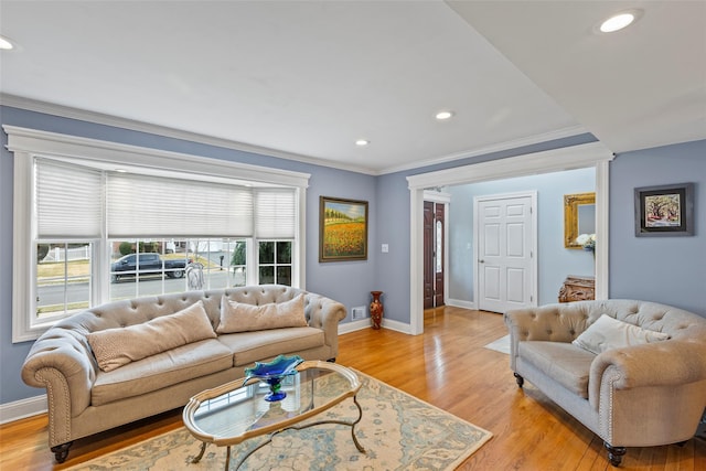 living area featuring plenty of natural light, light wood-type flooring, crown molding, and baseboards