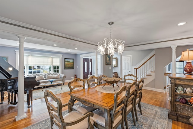 dining area with light wood finished floors, stairway, crown molding, and decorative columns