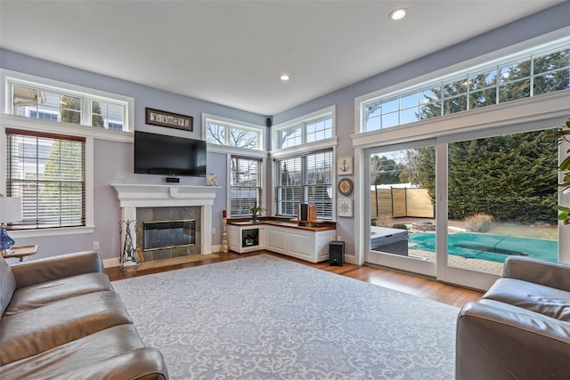 living room with a tiled fireplace, recessed lighting, light wood-type flooring, and baseboards