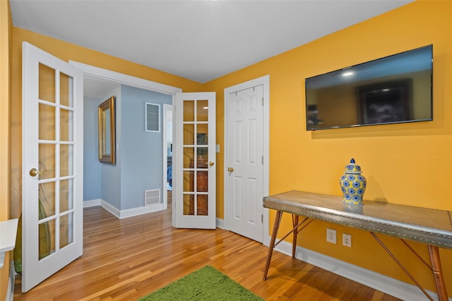 doorway featuring wood finished floors, french doors, visible vents, and baseboards