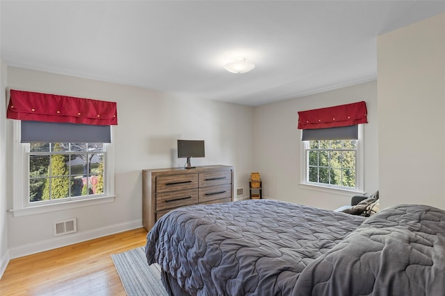 bedroom with visible vents, baseboards, and wood finished floors