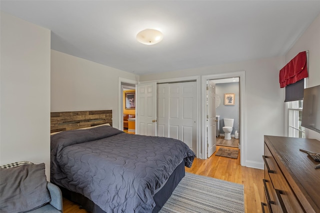 bedroom featuring ensuite bathroom, baseboards, light wood-type flooring, and a closet