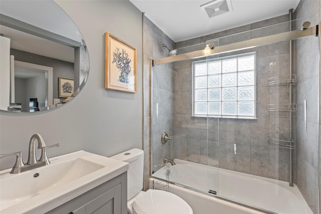 bathroom with visible vents, toilet, vanity, and bath / shower combo with glass door